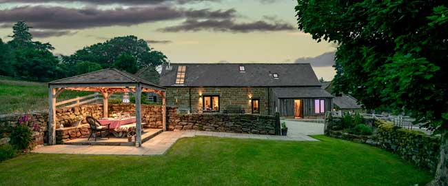Luxury holiday cottage with private walled garden and covered al fresco dining area at dusk
